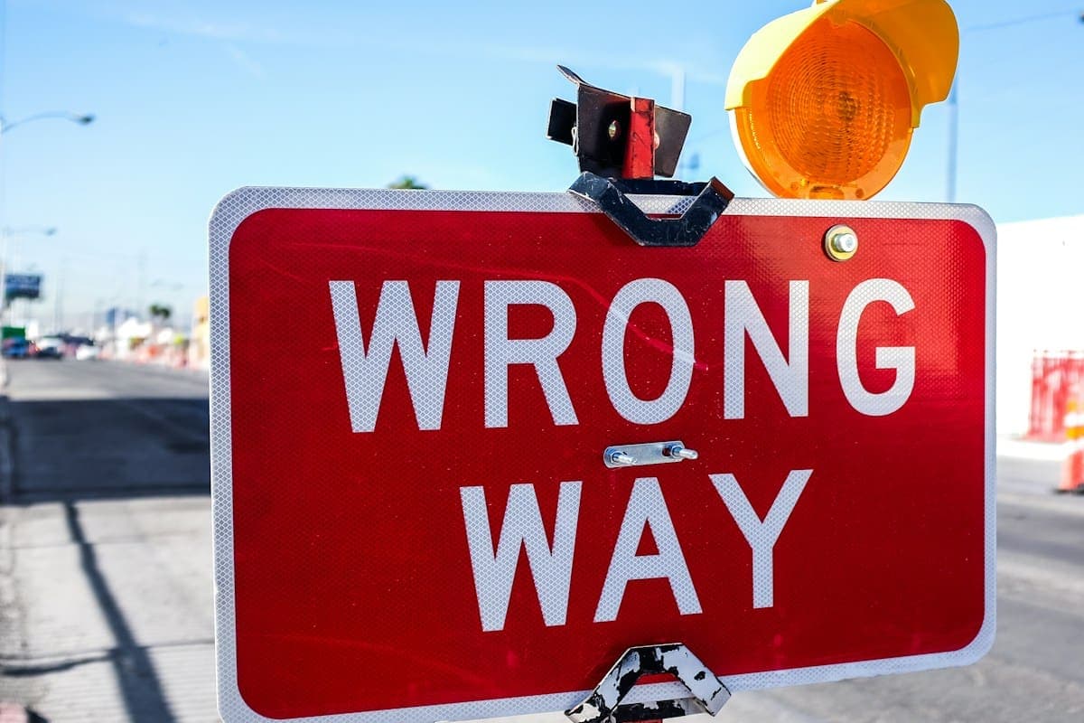 A red “Wrong way” road sign with an amber warning lamp