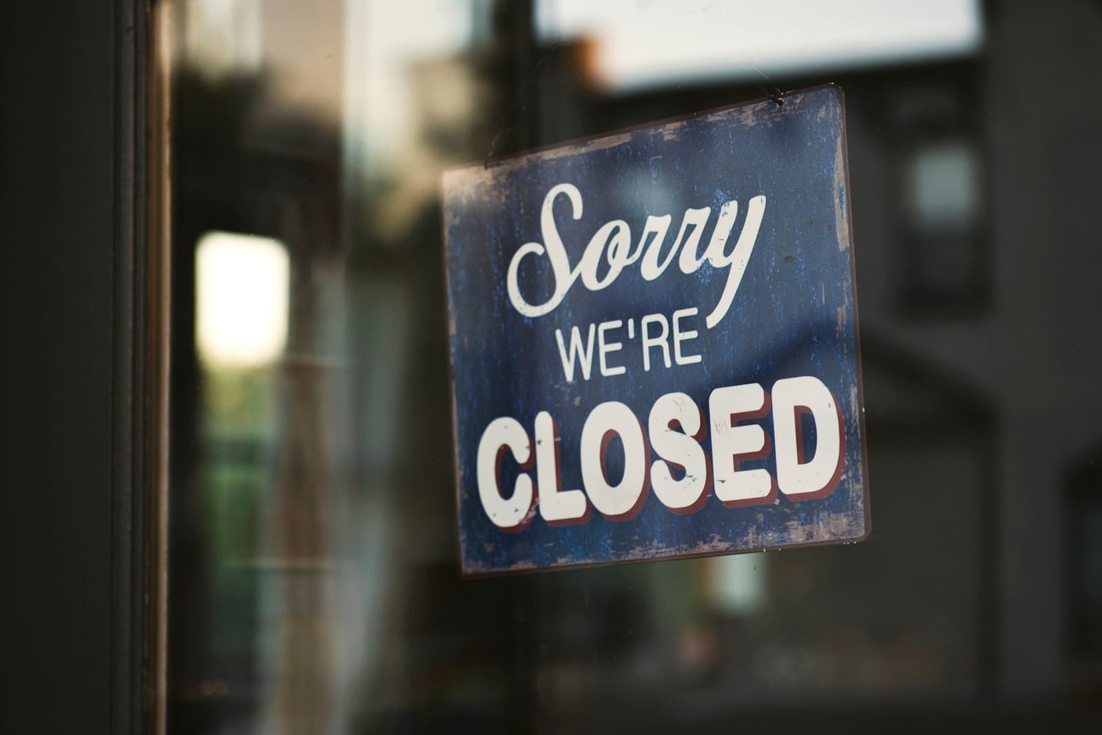 A “Sorry, we’re closed” sign hanging on a glass door
