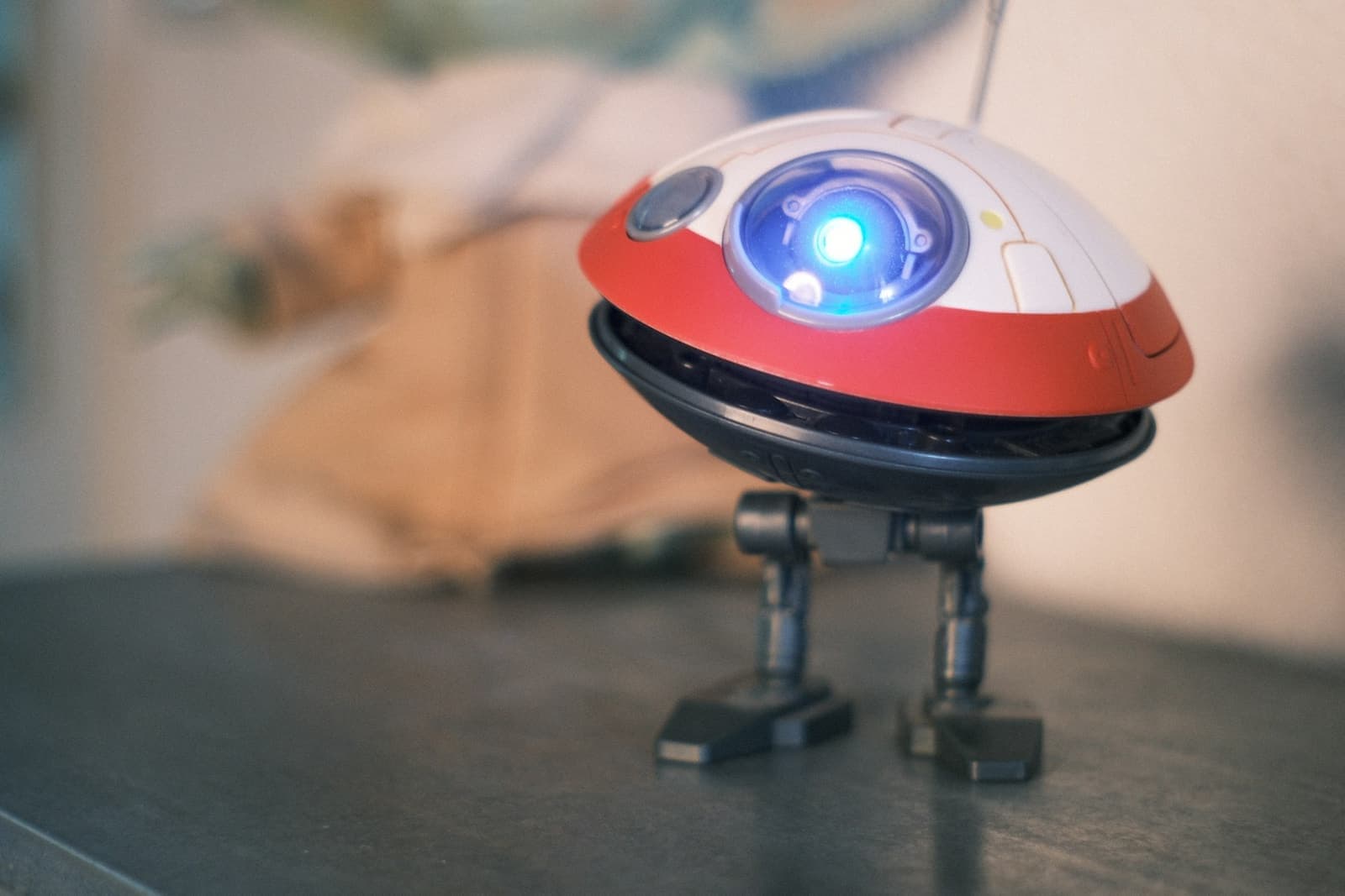 A toy robot with a red and white body and a glowing blue eye
