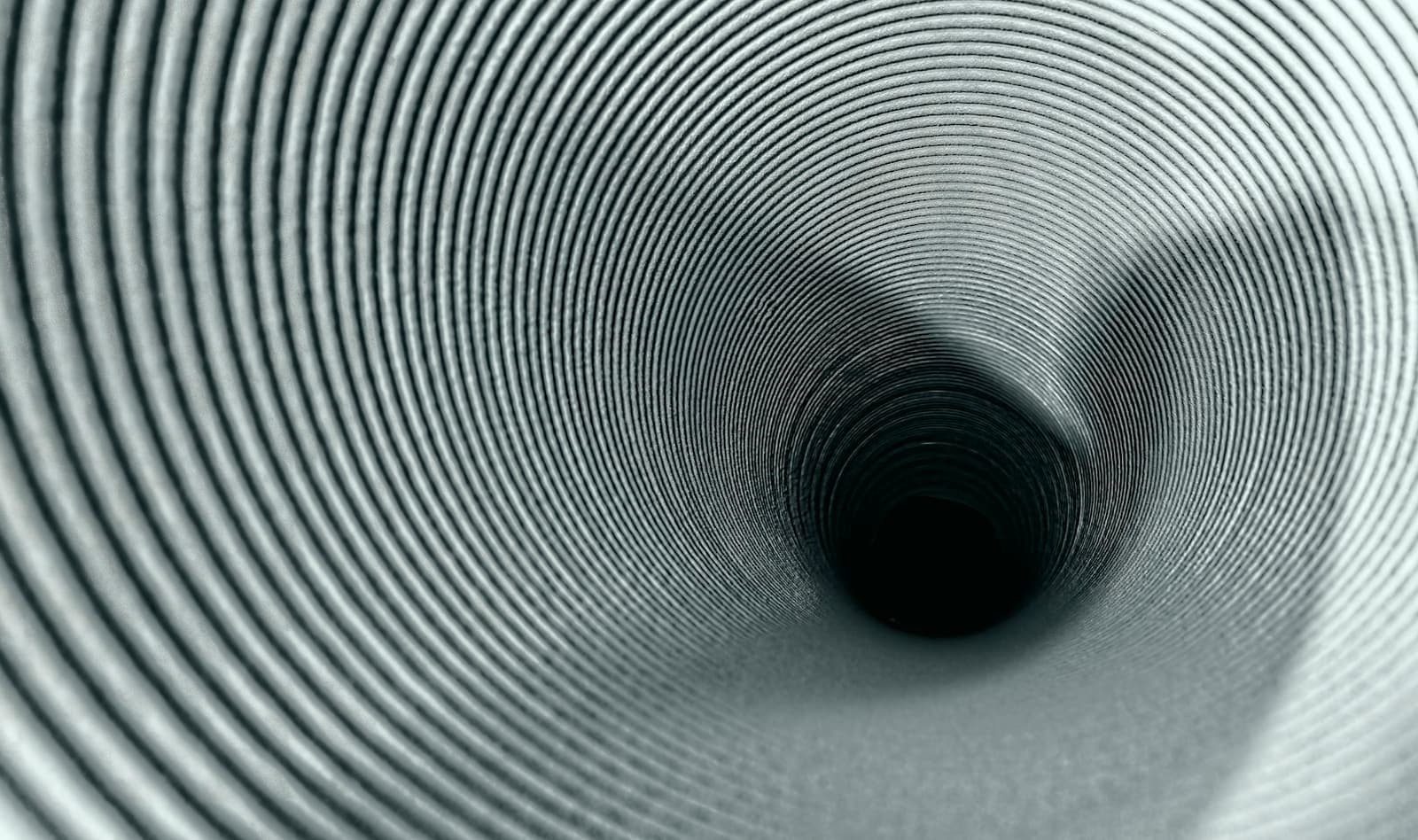 A round grey tunnel with concentric ribs narrowing to a dark opening
