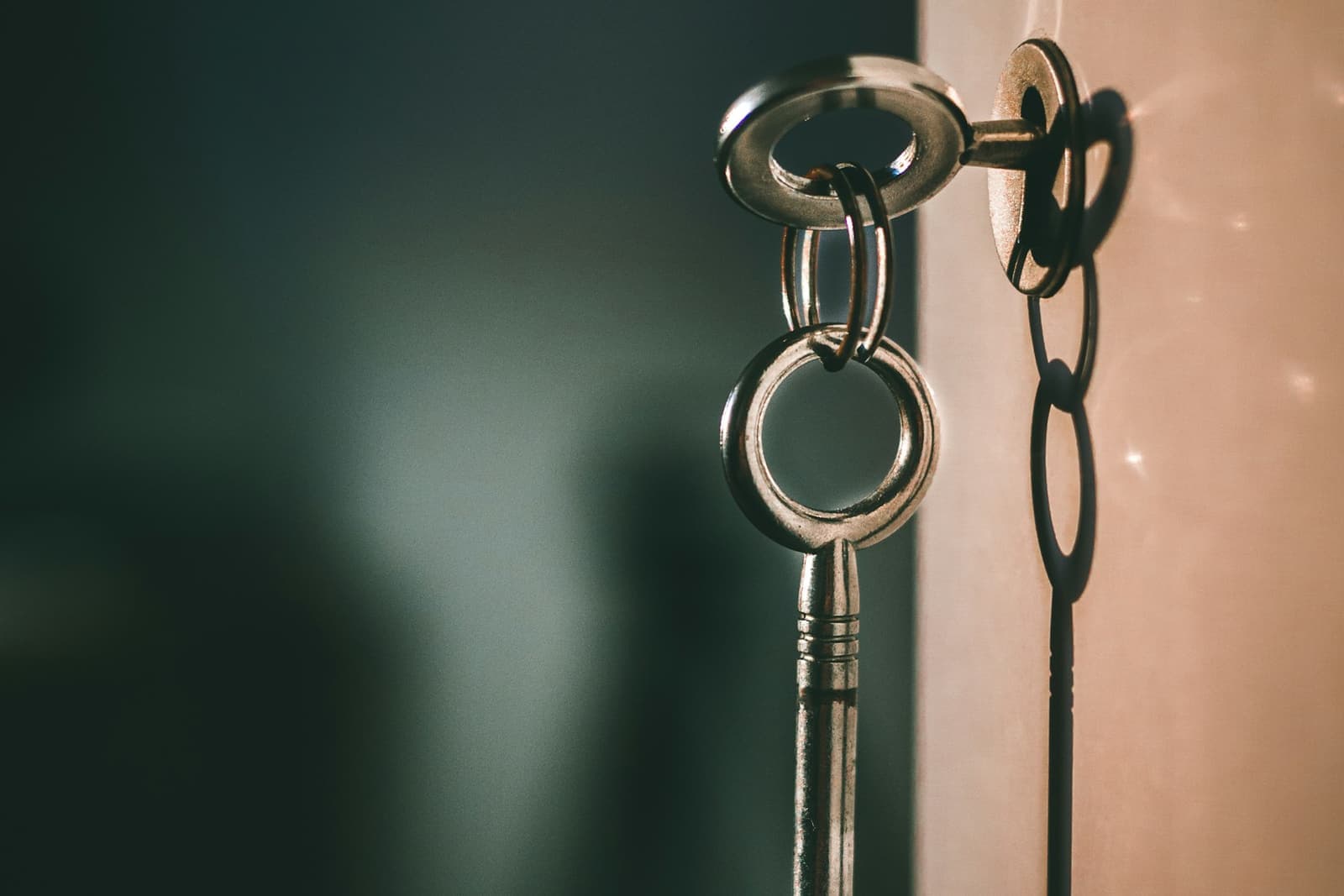 A metal key in a lock, casting a shadow on the wall