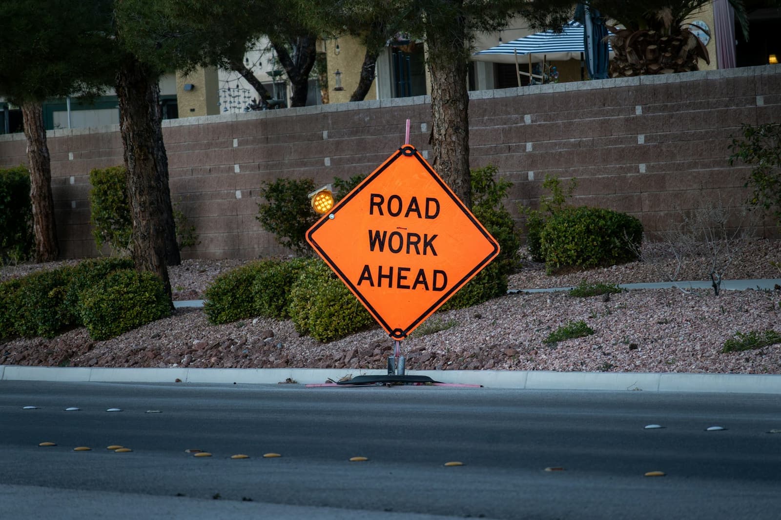 An orange “Road Work Ahead” sign beside a road